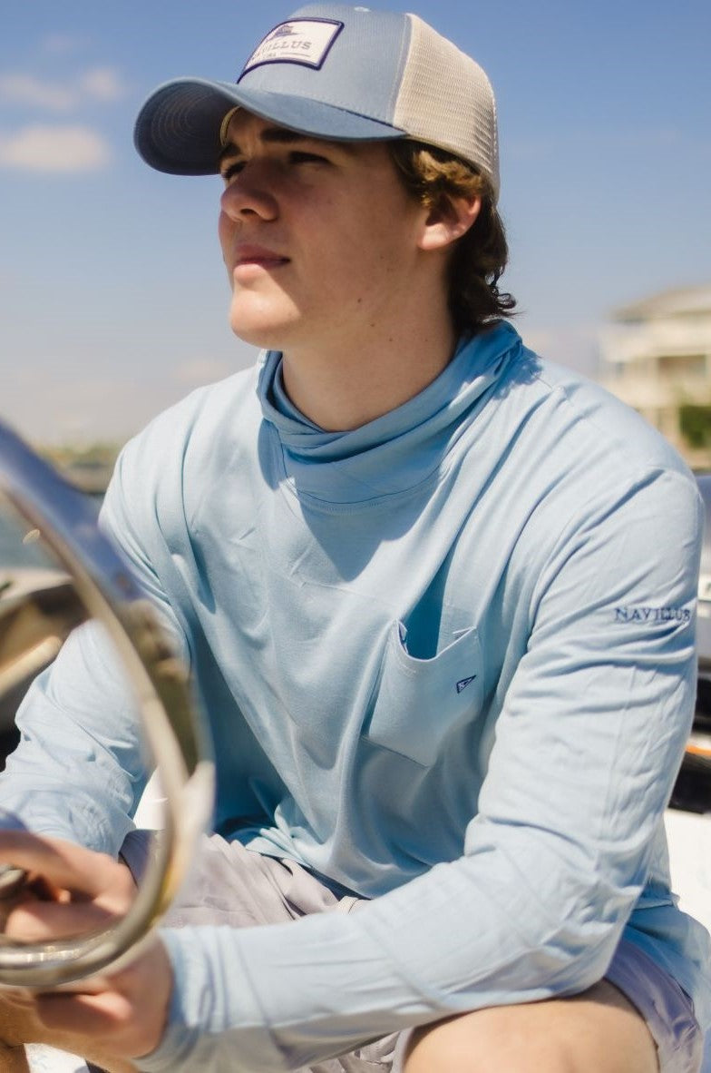 Model on a boat wearing the light ocean blue angler bamboo hoodie.